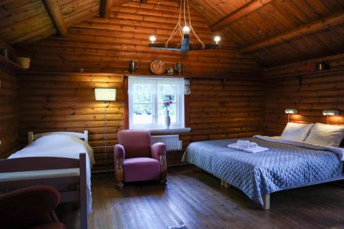 a bedroom with two beds and a chair in a log cabin at Luthagård in Äng