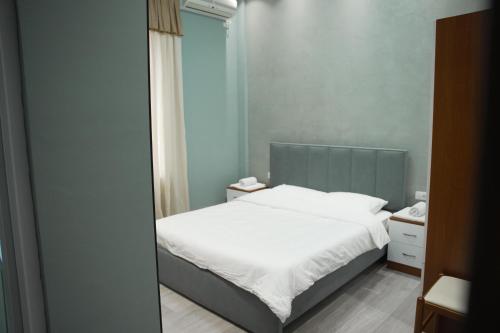 a bedroom with a white bed and a mirror at Hotel haliti kukes in Kukës