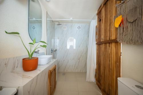 a bathroom with an orange potted plant on the counter at Casa pumara loft in Kerobokan
