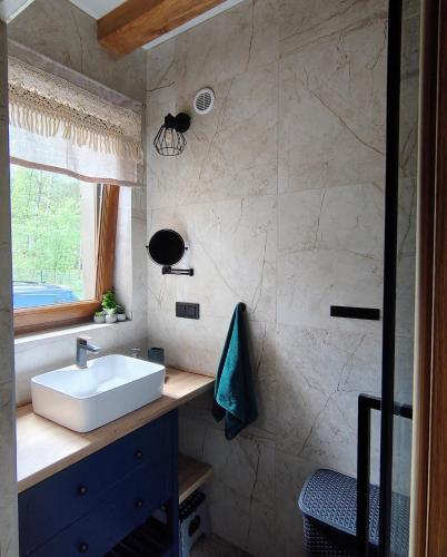 a bathroom with a white sink and a window at Domek na wynajem Lgiń in Wschowa