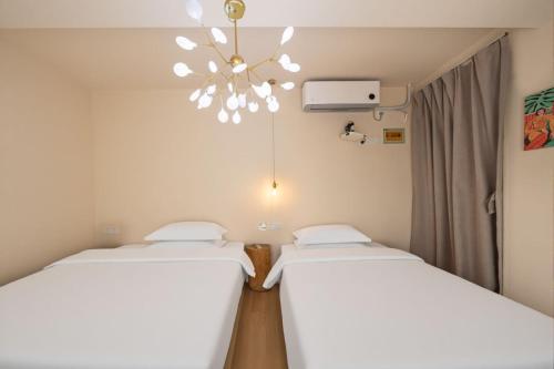 two beds in a room with a chandelier at Shanghai WanTing Villa Hotel in Shanghai