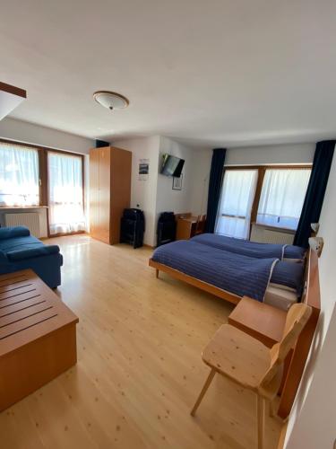 a bedroom with a bed and a couch and a table at Garní Ladinia in Pescul