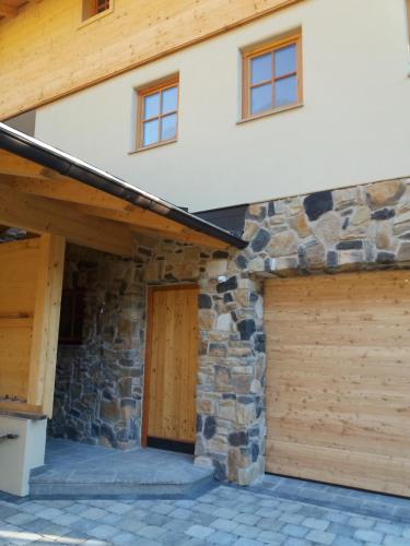 a house with two garage doors and a stone wall at Das Prinzis in Lofer