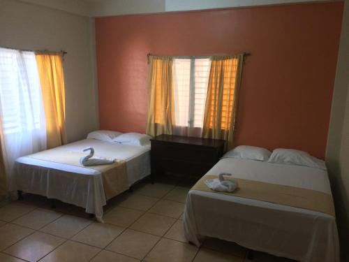 a bedroom with two beds and two windows at Hotel Casa Marina in La Ceiba