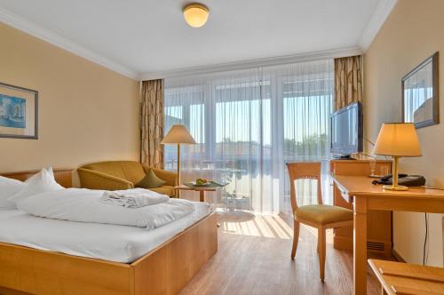 a hotel room with a bed and a desk and a television at Hotel Bayerischer Hof in Bad Füssing