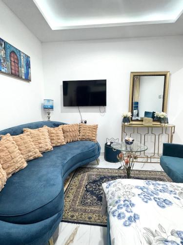 a living room with a blue couch and a tv at Velmora Villas room 14 in Abu Dhabi