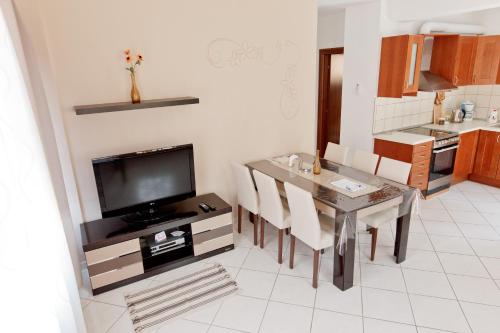 a kitchen with a dining room table with chairs and a television at Villa Fun & Sun in Limenaria