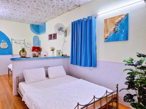 a bed in a room with blue curtains at Ben Guesthouse Phu Quoc in Phú Quốc
