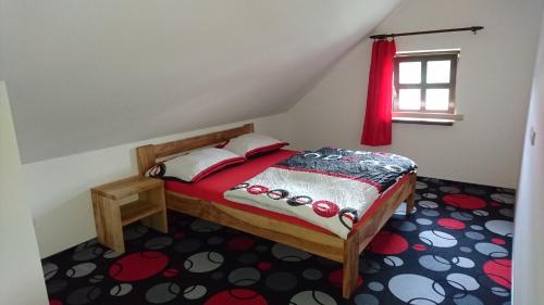 um quarto com uma cama com lençóis vermelhos e uma janela em Penzion Krkonoše em Mladé Buky