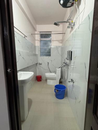a white bathroom with a toilet and a sink at Living Roots Lodge in Cherrapunji