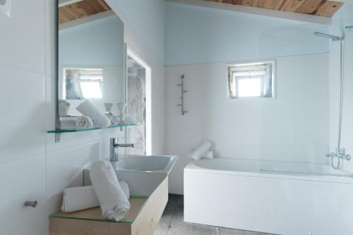 a white bathroom with a sink and a tub at Casa do Baleeiro in Calheta de Nesquim