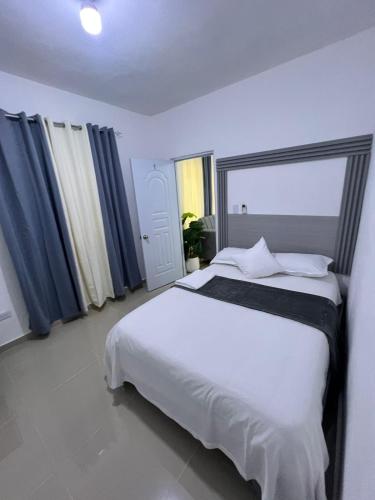 a bedroom with a large white bed with blue curtains at Boutique Hotel in Pedernales
