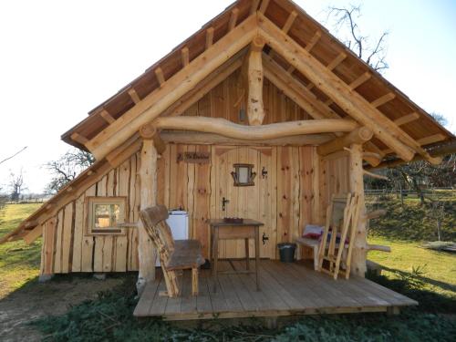 a large wooden cabin with a table and a chair at Glamping Organic Farm Slibar in Tržič