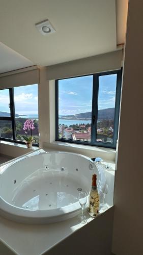 a bathroom with a tub with two wine glasses and windows at O NAUTICO suites in Cabana de Bergantiños