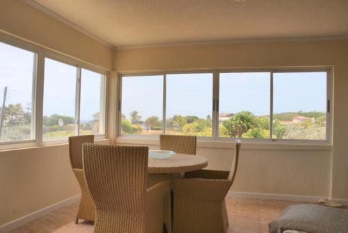 a dining room with a table and chairs and windows at Mermaid Apartments in Saint Philip