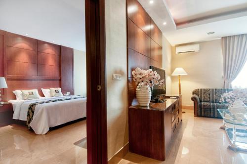 a hotel room with a bed and a vase of flowers at Grand Sakura Hotel in Medan