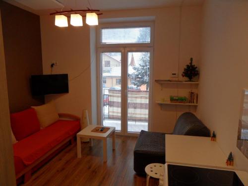 a living room with a red couch and a window at Apartament Kraszewskiego in Krynica Zdrój