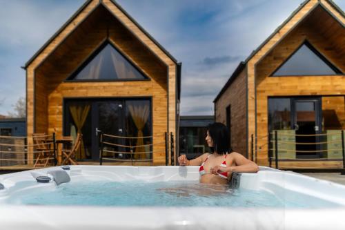 eine Frau sitzt in einem Whirlpool vor einem Haus in der Unterkunft Ypsilon - Pixel in Târgu Secuiesc