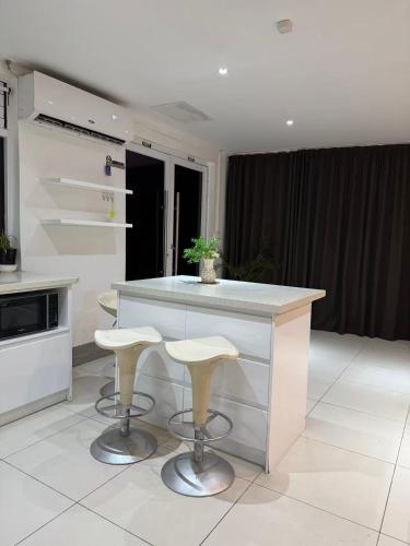 a kitchen with a white counter and stools in it at island payless private room in Nadi