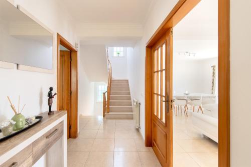 a kitchen and dining room with a staircase in a house at Lisbon Coastal Retreat in Charneca