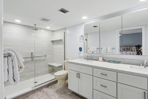a white bathroom with a shower and a toilet at Land's End 8-301 Beach Front in St. Pete Beach