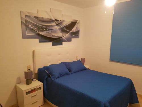 Un dormitorio con una cama azul y una pintura en la pared en Alondras Playa Denia, en Denia