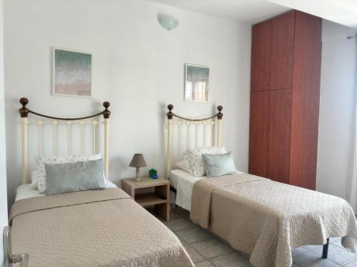 a bedroom with two beds and a table with a lamp at Annalisa Studio & Apartments in Skala