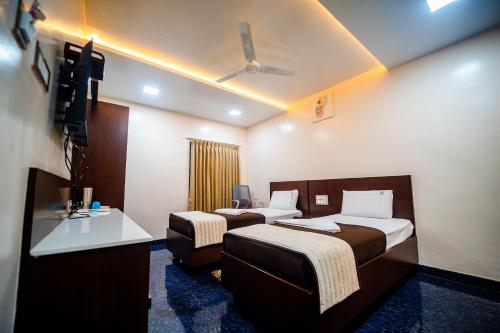 a hotel room with two beds and a television at V V Residency in Thanjāvūr