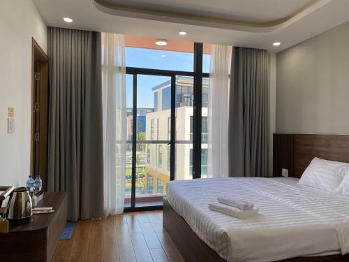 a bedroom with a large bed and a large window at MeySunset Hotel Phu Quoc in Phú Quốc