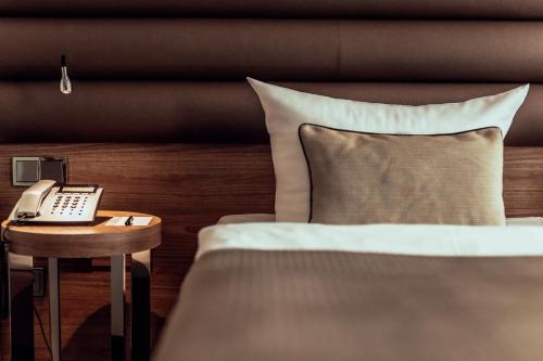 ein Schlafzimmer mit einem Bett und einem Telefon auf einem Tisch in der Unterkunft Hotel Ross in Schweinfurt