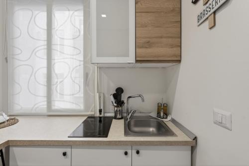 a kitchen with a sink and white cabinets at Pompei Luxury Suites-Near Ruins in Pompei