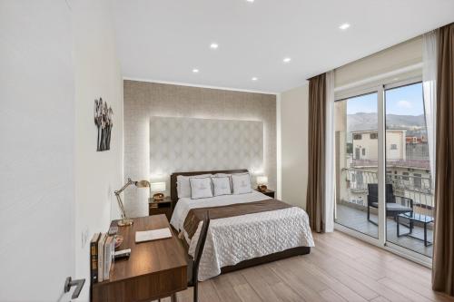 a bedroom with a bed and a desk and a balcony at Pompei Luxury Suites-Near Ruins in Pompei