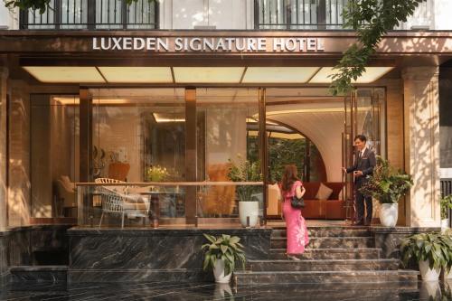 a man and a woman standing outside of a hotel at Luxeden Classic Hotel in Hanoi