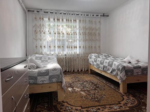 a bedroom with two beds and a window at Guest house TESKEI in Bokonbayevo
