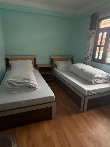 two twin beds in a room with wooden floors at Hotel River View in Syābru Bensi