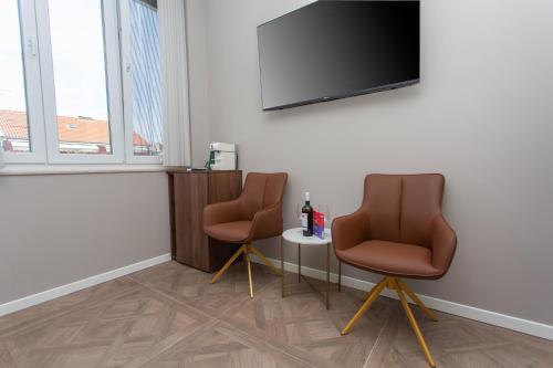 a room with two chairs and a tv on a wall at Luxury Rooms by Iva in Zadar