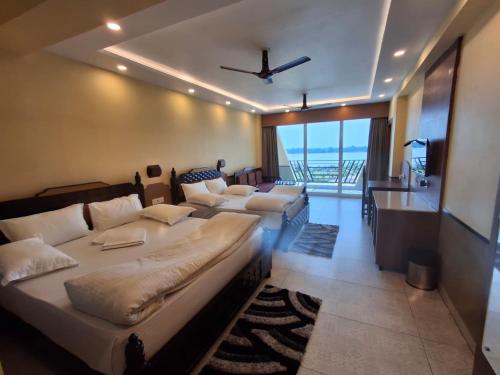 a bedroom with two beds and a balcony with the ocean at Sher Bengal River Resort - Kolaghat in Kolaghat