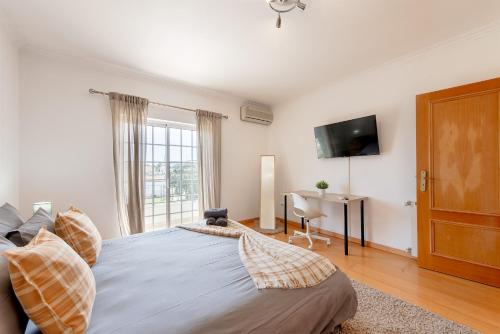 a bedroom with a bed and a desk and a television at Lisbon Coastal Retreat in Charneca