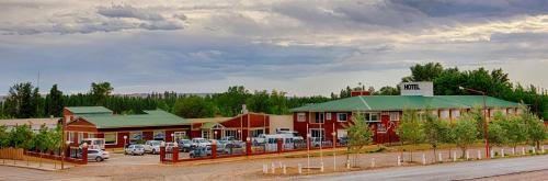 a building with cars parked in a parking lot at Hotel Sol del Añelo in Añelo