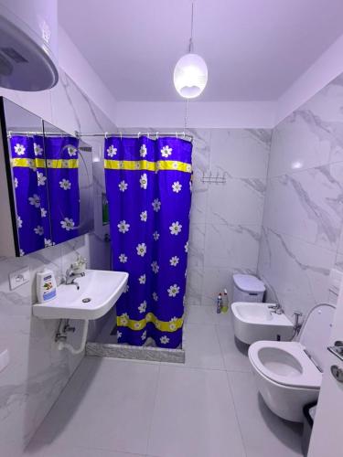 a bathroom with a toilet and a blue shower curtain at Luxurious seaside apartment in Sakës