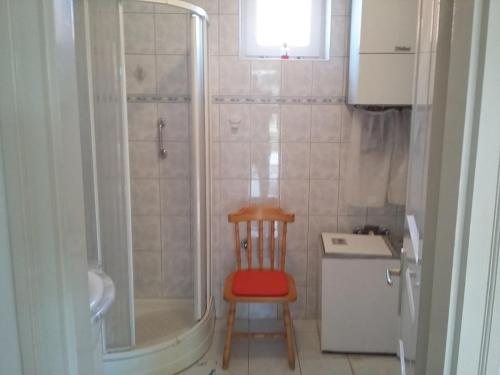 uma pequena casa de banho com um chuveiro e uma cadeira de madeira em GESZTENYÉS Vendégház em Harkány