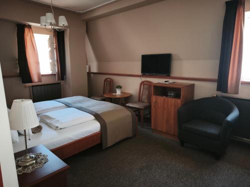 a bedroom with a bed and a chair and a television at Duna Panzió in Győr