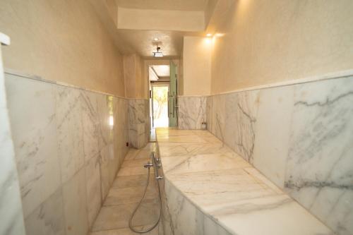 a corridor of a bathroom with white marble walls at Villa bord du lac takerkoust marrakech , 9 Suites de Luxe & événementiel in Wawizelt