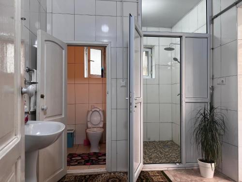 a bathroom with a toilet and a sink and a shower at Guest house TESKEI in Bokonbayevo