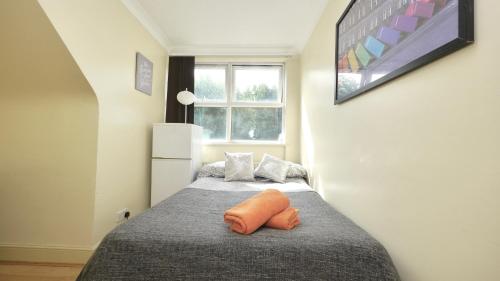 a bedroom with a bed with an orange pillow on it at 24/7 London Hostel in London