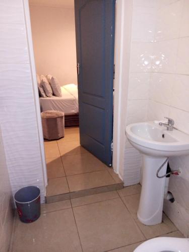 a bathroom with a sink and a toilet and a bed at Lancaster Guest House in Boksburg
