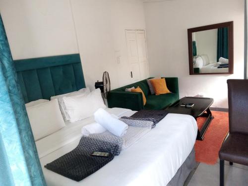 a bedroom with a bed and a couch and a mirror at Lancaster Guest House in Boksburg