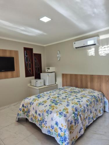 a bedroom with a bed with a floral bedspread at Suíte Praia Seca com ar condicionado in Araruama