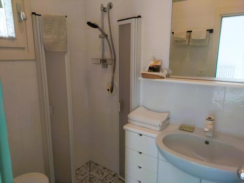 a white bathroom with a shower and a sink at B&B Casa Corbezzolo in Procchio