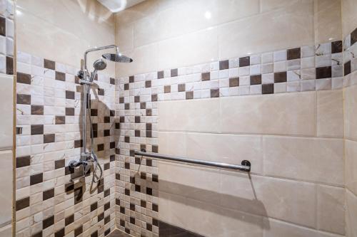 a bathroom with a shower with tiled walls at Taleen Serviced Apartments Granada- تالين غرناطة للشقق المخدومة in Riyadh